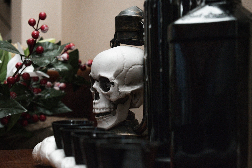 a skull statue sitting on top of a table next to a bottle