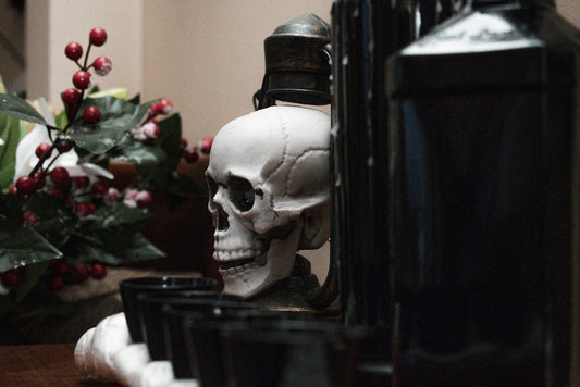 a skull statue sitting on top of a table next to a bottle